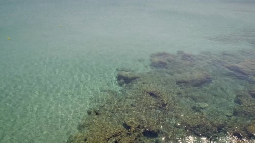 Aerial view of beach shore with rocks and very calm water in Greece.