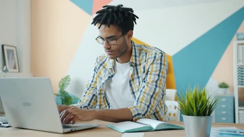 Tired Afro-American Man Working with Laptop Computer in Office Suffering From Headache