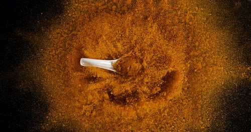 Turmeric, curcuma longa, Powder Exploding against Black Background, Indian Spice, Spoon
