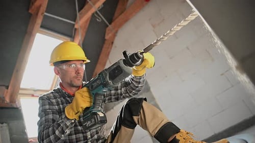 Travailleur forant un trou de mur utilisant une perceuse