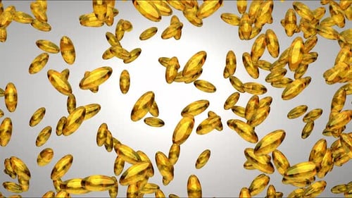 Golden Capsules Falling Against White Background