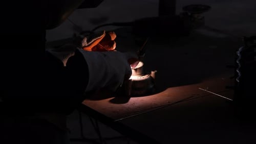 Professional men wearing welding mask and gloves work in home workshop with arc welding and argon.