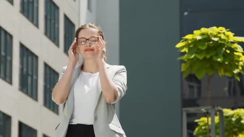 Young Woman Holds Glasses in Urban Setting