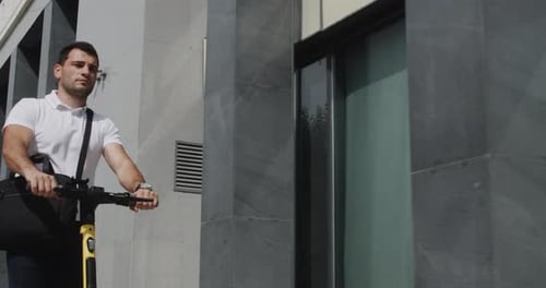 Hombre guapo montado en una moto ecológica con maletín en una calle urbana