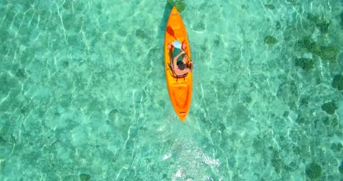 Aerial drone view of a man and woman couple kayaking around a tropical island