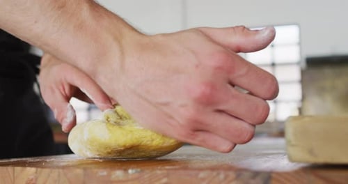 Chef caucásico amasando masa en una mesa de cocina