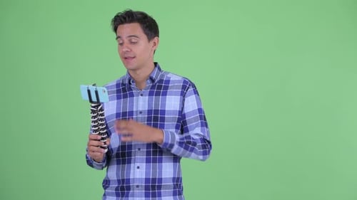 Young Adult Filming Himself with Mobile Phone on Tripod