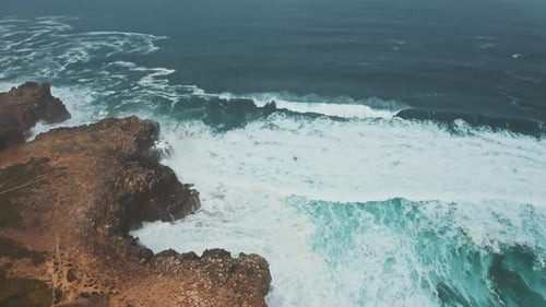 Wild ocean waves crashing againt coastal cliffs and into the caves shot by drone