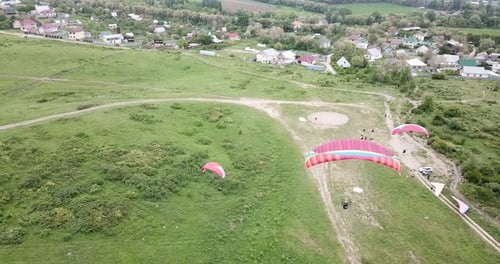 Paragliders Soaring Over Green Rural Landscape on Overcast Day