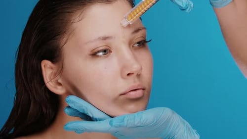 Cosmetologist Applies Liquid to Forehead of Young Woman