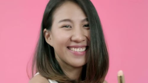 Woman Applies Lipstick on Pink Background