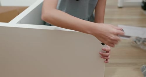 Young Woman Assembling Furniture at Home