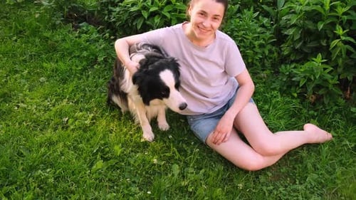 Woman Sits with Dog on Green Grass