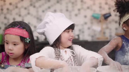 Gruppe von Kindern, die gemeinsam Kuchen im Klassenzimmer backen, multiethnische Jungen und Mädchen machen glücklich beim Backen.
