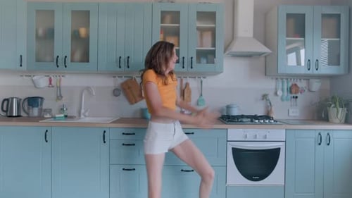 Young Woman Energetically Dancing in her Kitchen