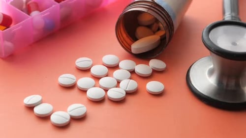 Close Up of White Pills Spilling on Orange Background