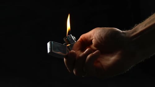 Männliche Hand feuert Flamme mit Zigarettenanzünder, Gasexplosion oder Brandstiftung