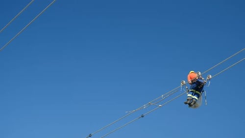 Trabalhador fixa bolas de aviação nos fios das linhas de energia