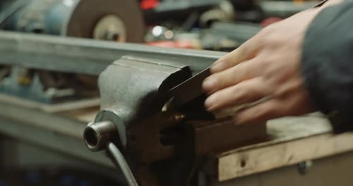 Adult Filing Metal Pipe Held in Vice