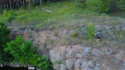 O Sillouette Man On The Rock. Homem Sillouette na rocha perto do rio com o pôr do sol
