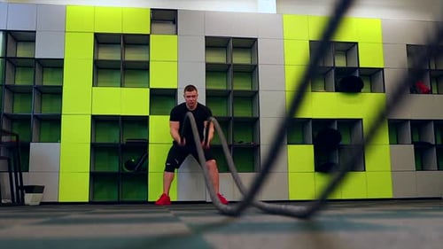Man Exercising with Battle Ropes in Gym