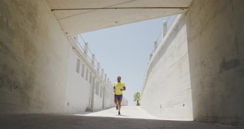 Man Running Through Bright Concrete Tunnel on Sunny Day