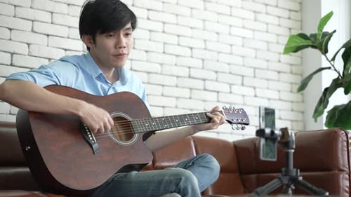 Young Man Singing and Playing Guitar at Home