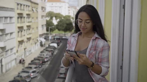 Young Woman On Balcony Using Mobile Phone