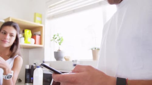Couple in Kitchen, Man Using Mobile Phone