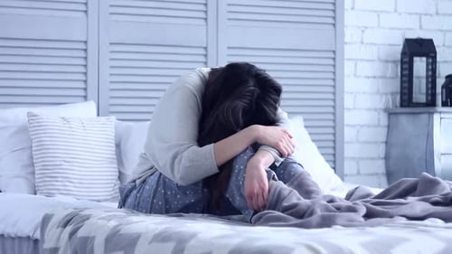 Unsuccessful Sad Woman Sitting at Grey Bedroom on Bed