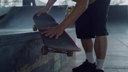 Skateboarder Holding Skate Board in Hands at Skate Park