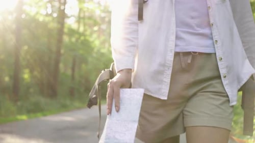 Woman Hiking with Map in Sunny Forest