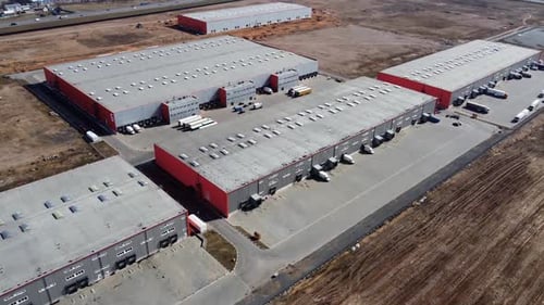 Semi trucks with cargo trailers standing on warehouses ramps for loading or unloading.