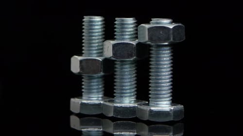 Bolts and Nuts Rotating on Black Surface