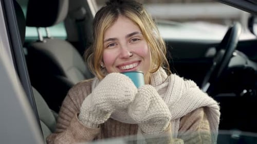 Smiling Woman Drinking Warm Drink in Car