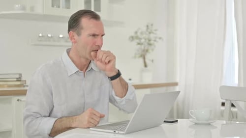 Man Working on Laptop, Coughing in Bright Room
