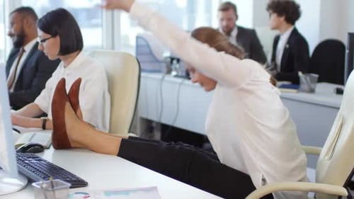 Businesswoman Relaxes by Stretching Legs on Desk