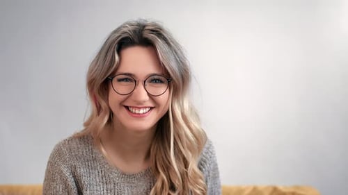 Smiling Woman Adjusts Her Blonde Hair Indoors