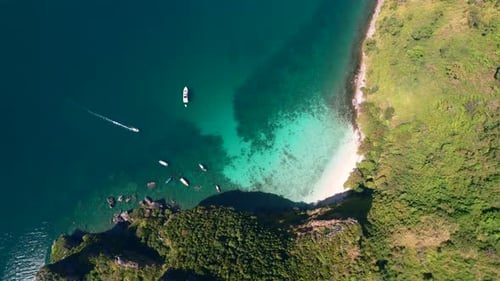 Luftaufnahme von oben nach unten eines Bootes, das durch wunderschönes türkisblaues Wasser in der Andamanensee fährt