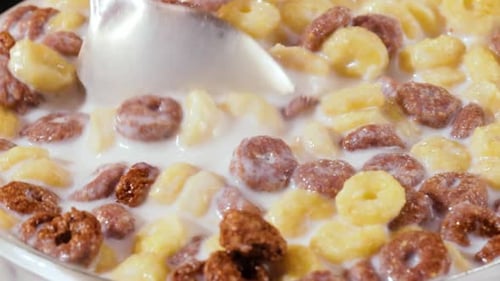 Stirring Cereal Circles in White Milk with Spoon