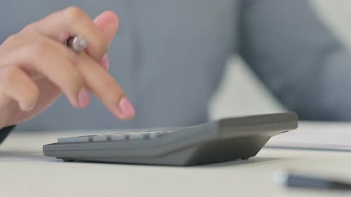 Close Up of African Woman Using Calculator Writing on Paper