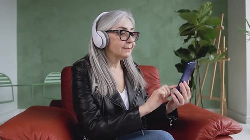 Senior Woman Enjoys Music with Phone and Headphones