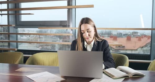 Concerned Woman Working on Laptop Computer and Looking Away Thinking Solving Problem at Office