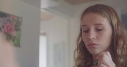 Teen Girl Applying Mascara in Front of Mirror