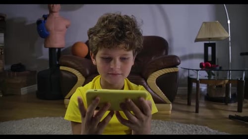 Boy Sits on Floor Playing Game on Phone