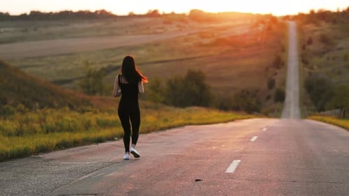 Woman Runs Along Country Road at Sunrise