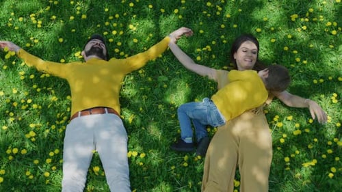 Happy Family Relaxing on Grass in Spring Meadow
