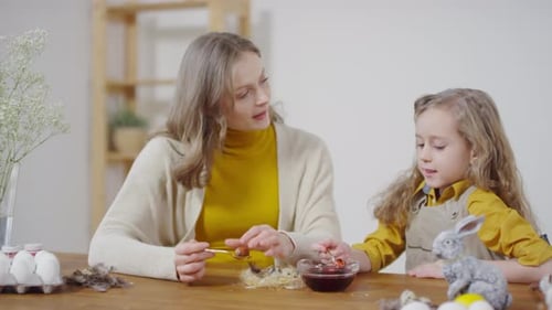 Caring Mother and Little Girl Dyeing Eggs for Easter