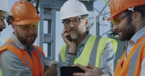 Ingeniero maduro hablando por teléfono inteligente durante una reunión en una central eléctrica