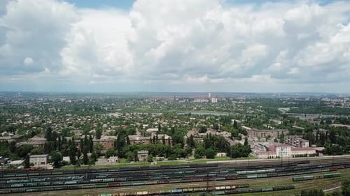 View of the railway station with cars. A blue sky with huge blocks loomed over the city.